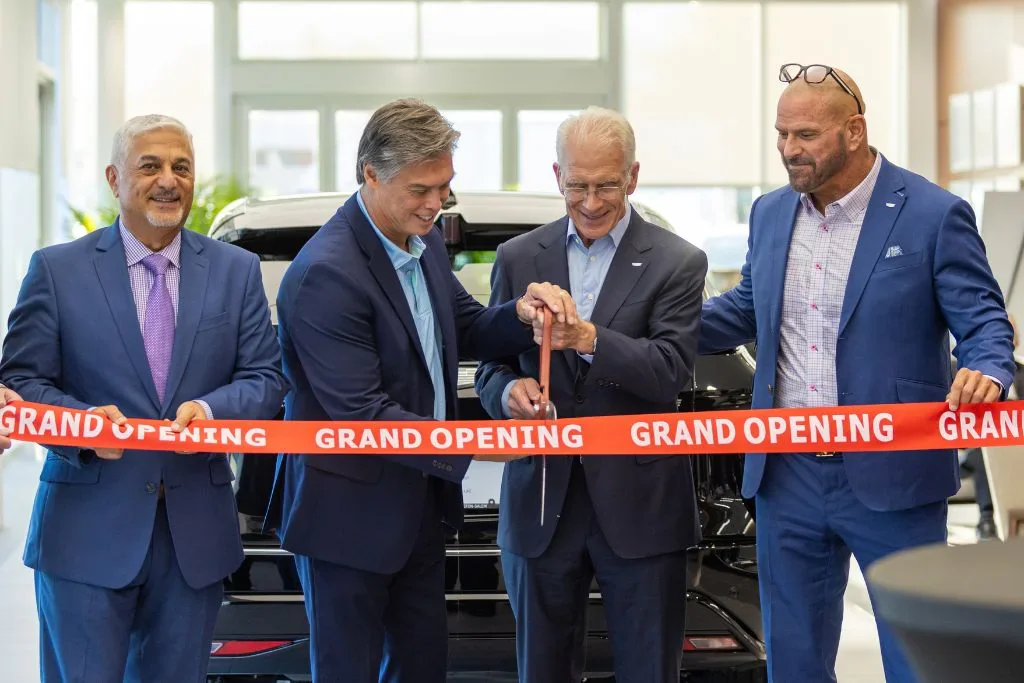 A grand opening event featuring three men cutting a ribbon