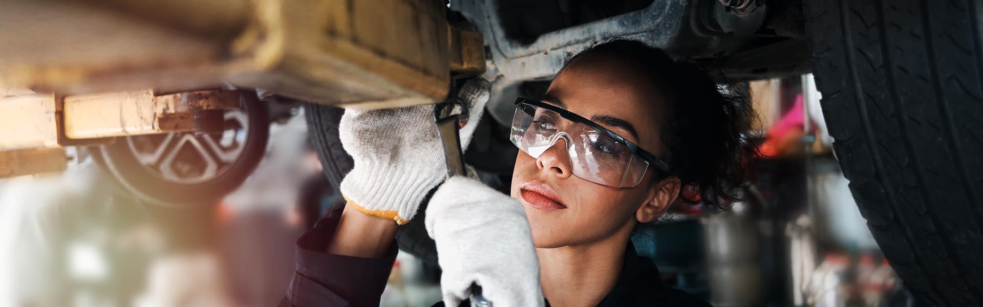 lady service technician working under the car